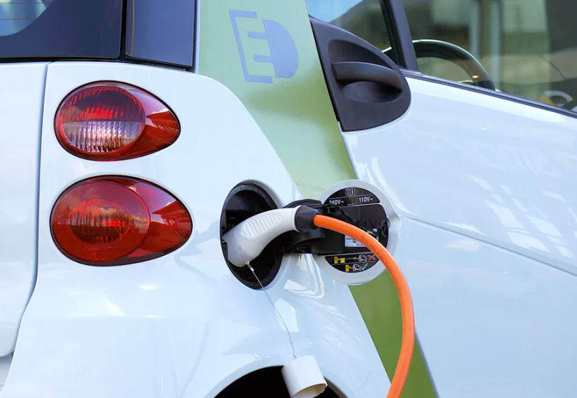 An electric vehicle being charged at a charging station, showcasing a sleek car plugged into a modern EV charger